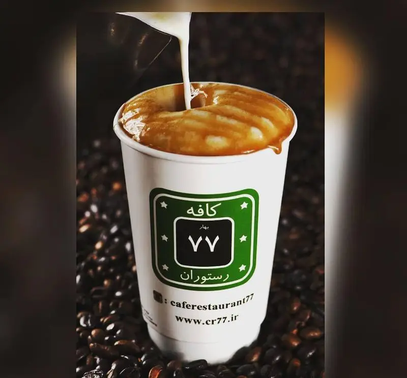 قهوه کارامل ماکیاتو خوش طعم از کافه رستوران ۷۷ با سس کارامل و شیر در حال ریختن، نوشیدنی گرم و دلپذیر رستوران و کافه ۷۷.
