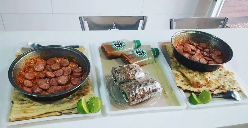 نمایی از صبحانه کامل و خوشمزه در رستوران و کافه ۷۷ شامل سوسیس بندری با نان داغ، نوشیدنی‌های تازه و دسرهای جذاب.