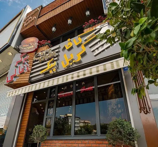 تصویری از نمای خارجی فست فود ب ب ک، با تابلوی درخشان ناف گریل، نماد برگر و طراحی زیبا، آماده پذیرایی از مشتریان.