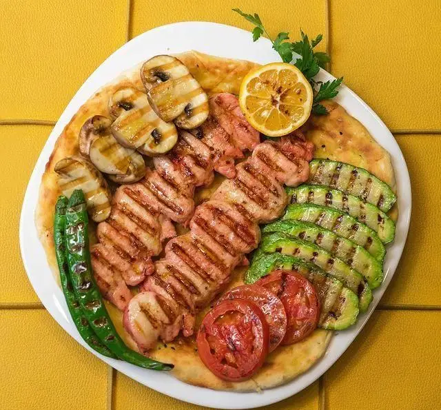 سینی کباب مرغ گریل با سبزیجات شامل قارچ، کدو، فلفل و گوجه کبابی روی نان، غذای خوشمزه فست فود ب ب ک.