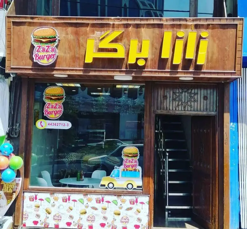 نمای بیرونی فست فود زازا برگر، با تابلوی درخشان و لوگوی همبرگر. تلفن تماس برای سفارش آنلاین انواع همبرگر و ساندویچ.