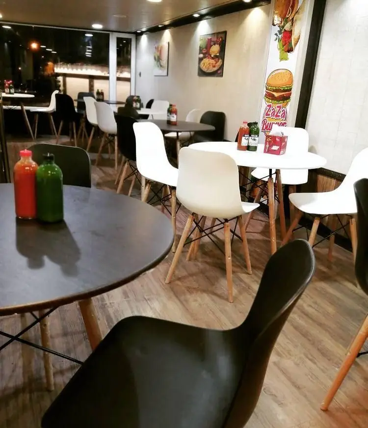 فضای داخلی دنج و مدرن فست فود زازا با میز و صندلی‌های شیک سفید و مشکی، مکانی عالی برای لذت بردن از غذاهای خوشمزه.