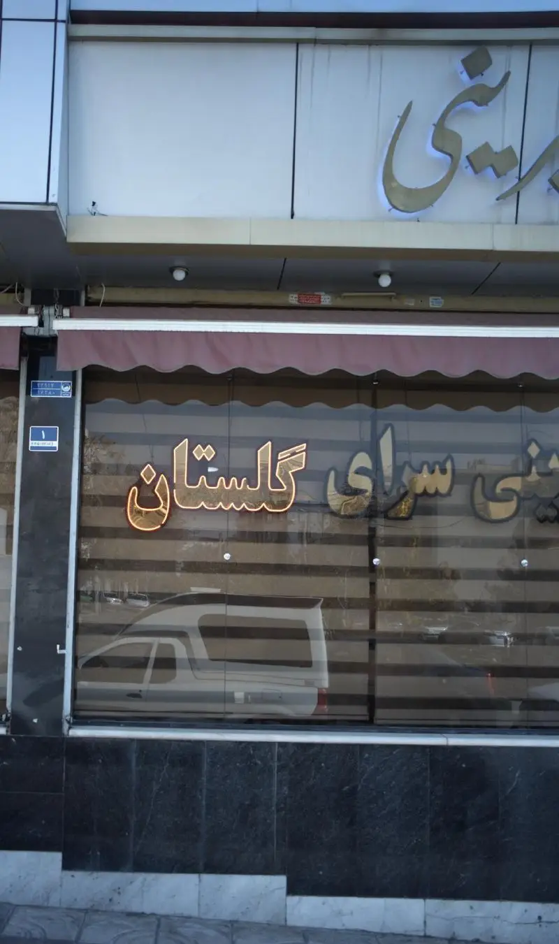 تصویر نمای بیرونی قنادی شیرینی گلستان با تابلوی نئون روشن و سایبان مغازه. فروشگاه شیرینی و قنادی گلستان.