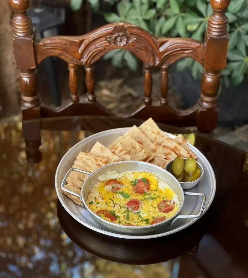 صبحانه خوشمزه کافه دلواز شامل املت، نان تازه و ترشی. لذت یک وعده صبحگاهی دلنشین در فضایی آرامش‌بخش.