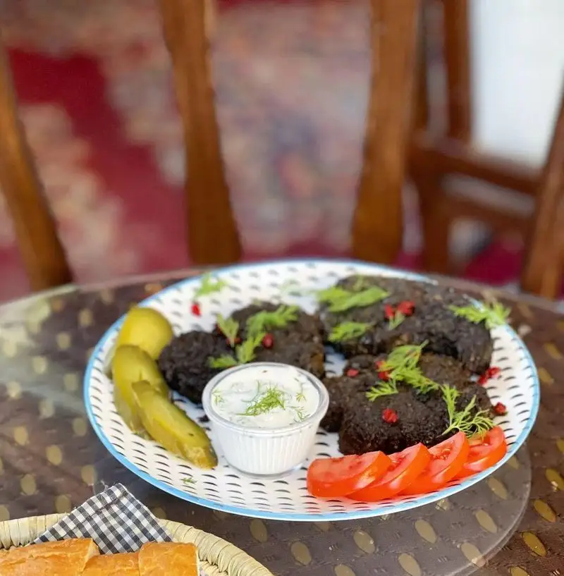 کافه دلواز: بشقاب کوکو سبزی سنتی با تزئین شوید و زرشک، همراه با سس ماست، برش گوجه و ترشی. غذایی سالم و خوش‌طعم.