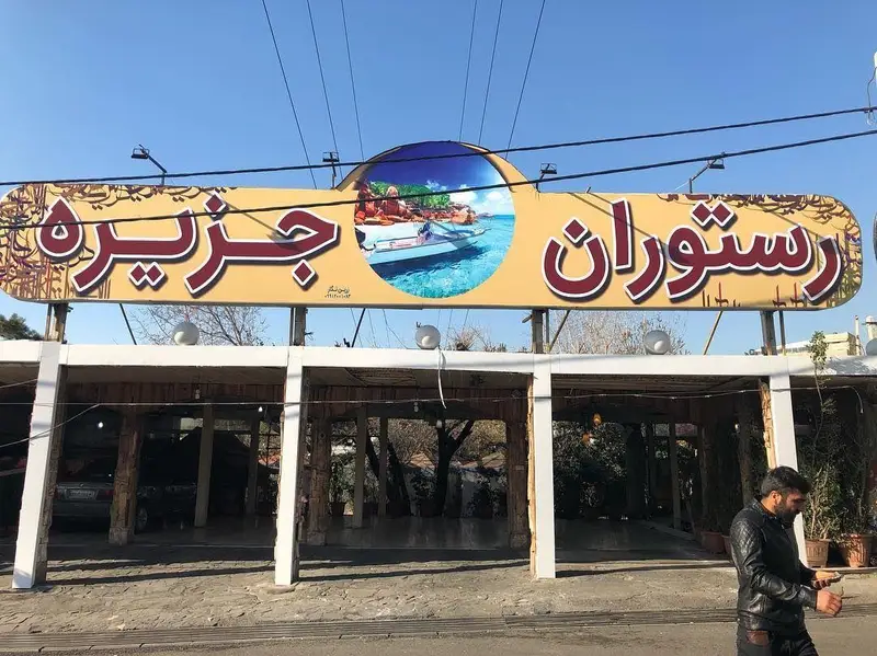 تابلو بزرگ ورودی رستوران جزیره، با نام و تصویر ساحلی شامل قایق و آب، مناسب برای جذب مشتریان و شناخت کسب و کار.