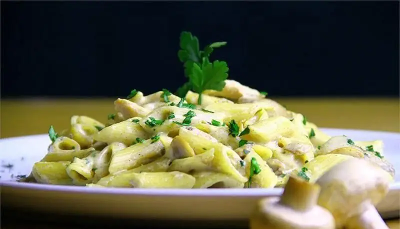 پاستا پنه خامه ای با مرغ و قارچ، تزئین شده با جعفری تازه، یک غذای لذیذ و محبوب از منوی متنوع رستوران ایتالیایی رومانا.