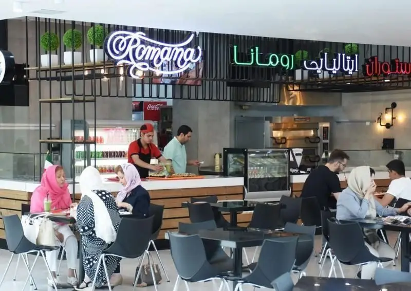 تصویری از محیط شیک و مدرن رستوران ایتالیایی رومانا با مشتریان و پرسنل، آماده‌سازی پیتزا و غذاهای خوشمزه.