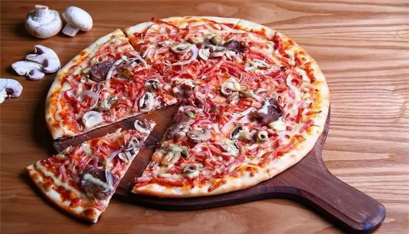 پیتزای ایتالیایی خوشمزه با قارچ تازه، ژامبون، پیاز و زیتون در رستوران رومانا، لذت یک غذای اصیل ایتالیایی را تجربه کنید.