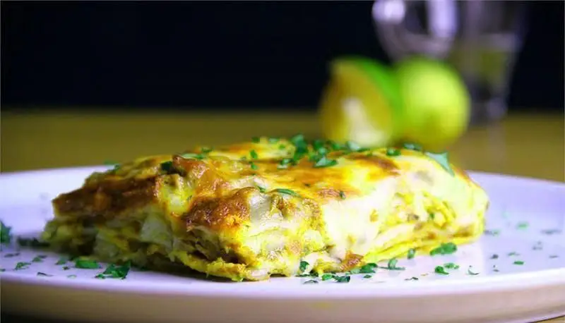 یک تکه لازانیای تازه و لذیذ با رویه پنیری طلایی و جعفری خرد شده، انتخابی عالی از منوی رستوران ایتالیایی رومانا.