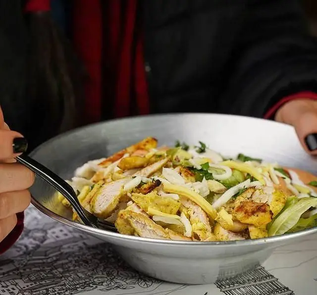 مشتری از سالاد یا پاستا مرغ گریل شده، کاهو و پنیر در رستوران ایتالیایی رومانا لذت می‌برد. غذایی تازه و خوشمزه.