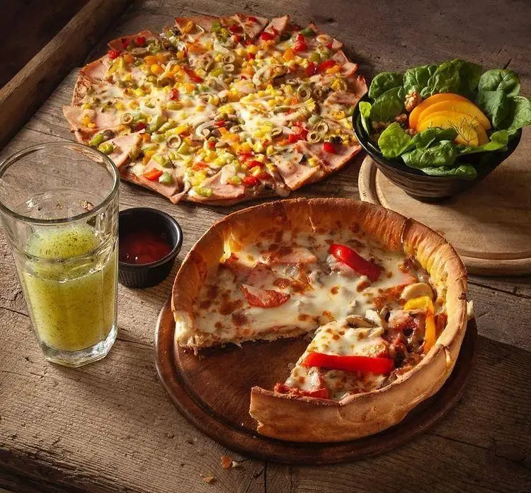 پیتزاهای متنوع فست فود باگت: پیتزا با مخلفات رنگی، پیتزا دیپ دیش با پنیر فراوان، سالاد تازه و نوشیدنی گوارا.