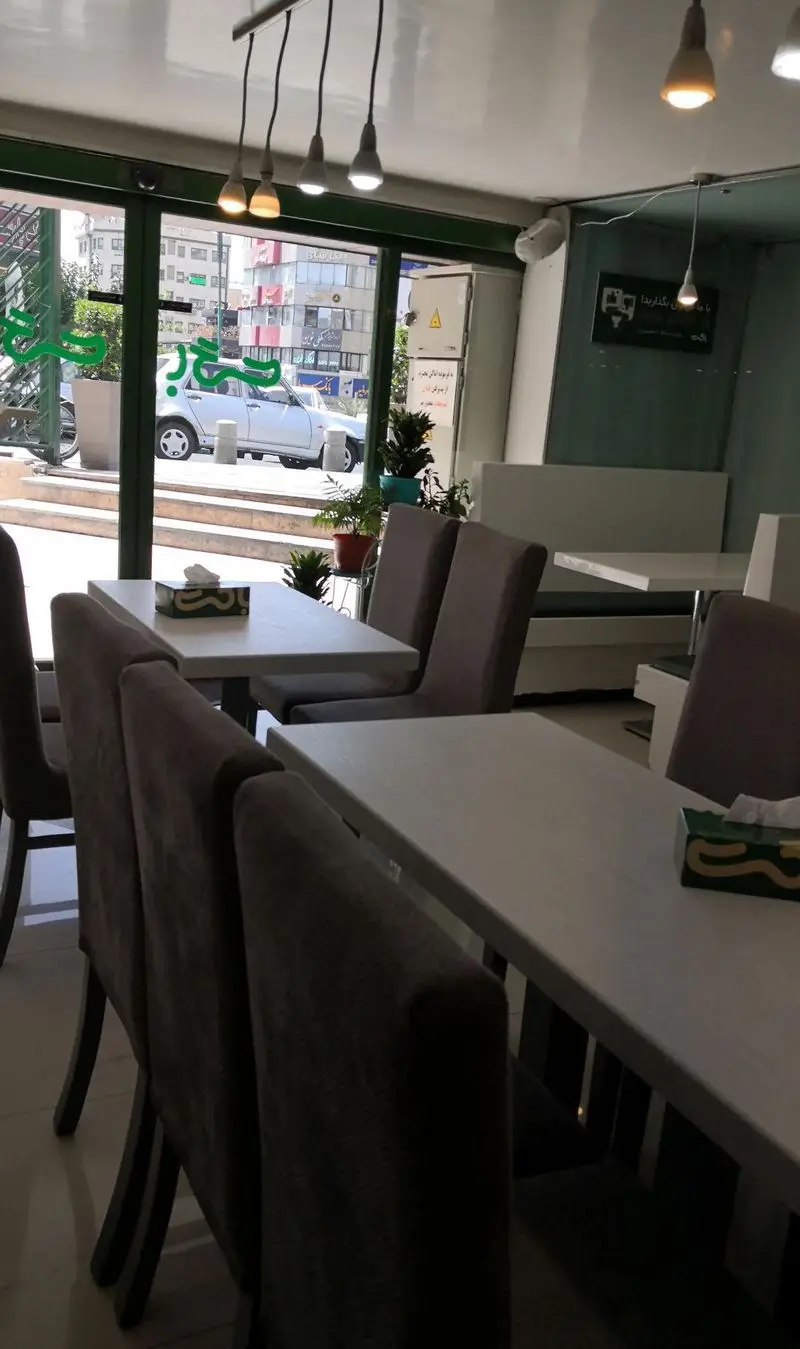 فضای داخلی روشن و دلنشین فست فود باگت با میز و صندلی‌های شیک، پنجره‌های بزرگ رو به شهر و محیطی آرامش‌بخش برای مشتریان.