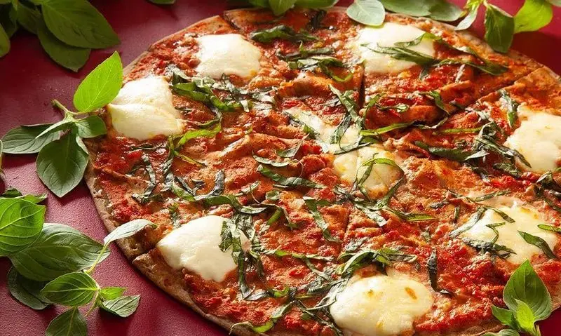 پیتزای مارگاریتا لذیذ فست‌فود باگت با سس گوجه، پنیر موزارلا ذوب‌شده و برگ‌های معطر ریحان تازه.