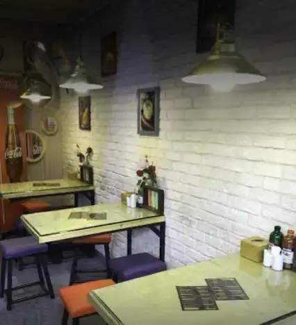 نمای داخلی فست فود سرزمین لقمه با دکوراسیون جذاب، میز و صندلی‌های رنگارنگ و دیوار آجری سفید، فضایی دنج و مدرن برای مشتریان.