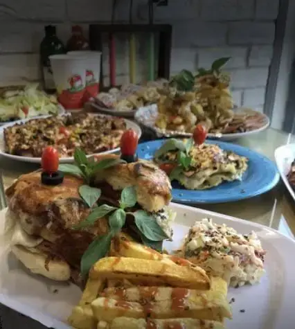 سفره‌ای رنگارنگ از بهترین غذاهای فست فود سرزمین لقمه شامل برگر، سیب زمینی، پیتزا و پیش‌غذاهای متنوع آماده سرو.