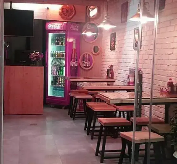 فضای داخلی فست فود سرزمین لقمه با میز و صندلی‌های چوبی، یخچال بزرگ نوشابه و دیوارهای آجری سفید، فضایی دلنشین برای مشتریان ایجاد کرده است.