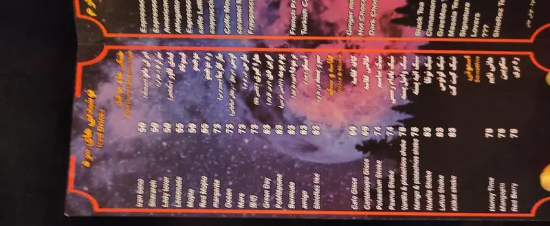 منوی کافه شیرز ShieRez cafe شامل نوشیدنی های خنک، شیک و اسموتی با قیمت‌ها. این منو در فضایی تاریک با تم ماه و درختان نمایش داده شده است.