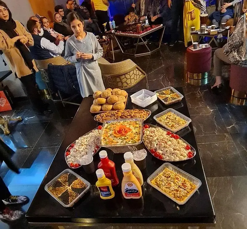 سفره رنگین و پر از غذاهای متنوع در کافه شیرز (ShieRez Cafe)، شامل انواع سالاد، نان و پیش‌غذا برای یک دورهمی دوستانه.