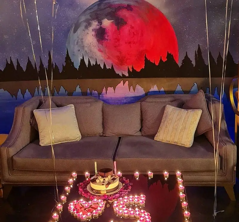 فضای رومانتیک و دلنشین کافه شیرز با دکوراسیون ماه و شمع‌ها برای جشن‌ها. شمع‌آرایی قلب و کیک تولد روی میز.