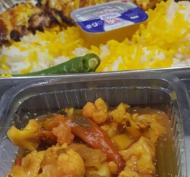 غذای کترینگ شاهین: چلوکباب جوجه با برنج زعفرانی، فلفل سبز و کره، همراه با ترشی گل کلم و هویج. یک غذای ایرانی خوشمزه.