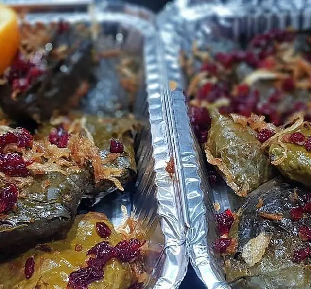 دلمه برگ مو و کلم، تزئین شده با زرشک و پیاز داغ، آماده در ظروف کترینگ. غذای ایرانی اصیل از کترینگ شاهین برای میزبانی شما.