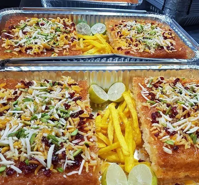 کترینگ شاهین: غذای مجلسی و خوشمزه ایرانی، شامل پلو زعفرانی با زرشک، خلال پسته و بادام، سیب‌زمینی سرخ‌کرده و لیمو.