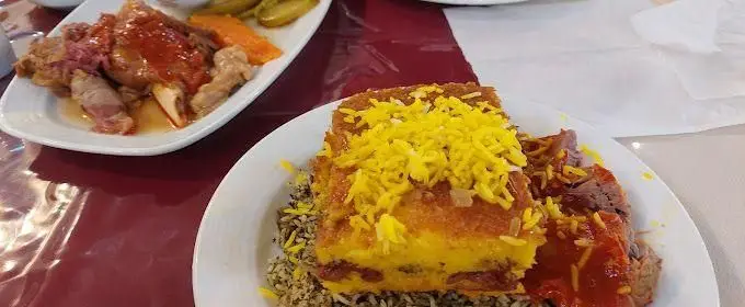 سفره‌ای از غذاهای اصیل رستوران خاتون شامل ته چین مجلسی و ماهیچه گوسفندی با پلو، طعمی فراموش‌نشدنی از آشپزی ایرانی.