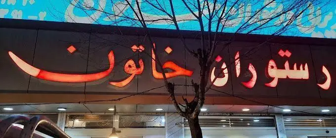 تابلوی نشان رستوران خاتون با چراغ‌های زیبا و روشن، پیغامی برای تجربه غذای ایرانی اصیل و لذیذ در تهران.