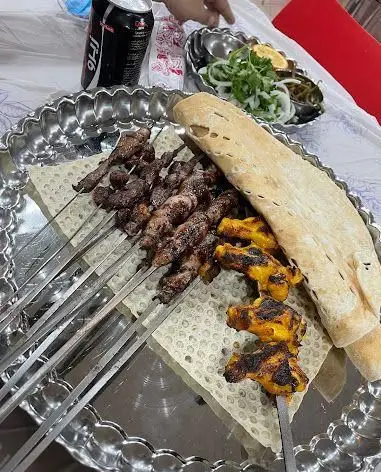 سینی پر از کباب جیگر، دل، قلوه و جوجه کباب با نان داغ و مخلفات در کبابی جیگر طهرون، یک غذای سنتی و لذیذ ایرانی.