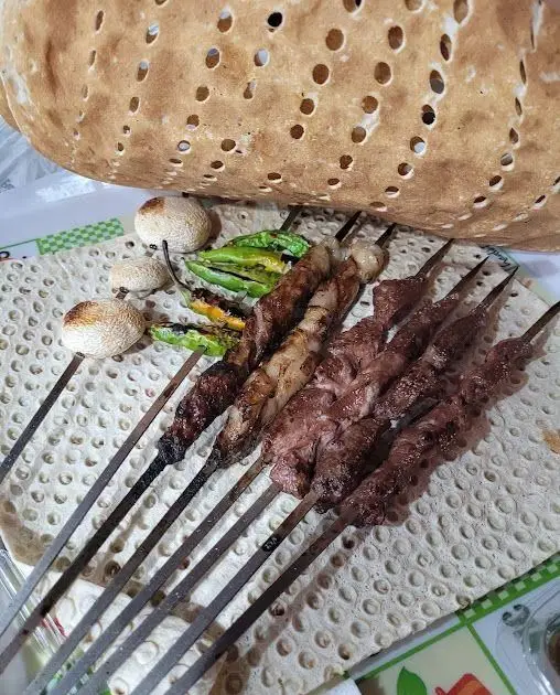 تصویری اشتهاآور از کباب‌های جگر و گوشت تازه و آبدار کبابی جیگر طهرون به همراه نان سنگک داغ و فلفل کبابی.