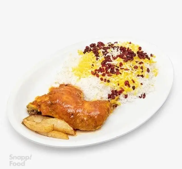 رستوران الف: ران مرغ خوش پخت و آبدار با سس مخصوص، همراه با زرشک پلو مجلسی و زعفرانی و سیب زمینی وِج، یک غذای ایرانی محبوب و لذیذ.