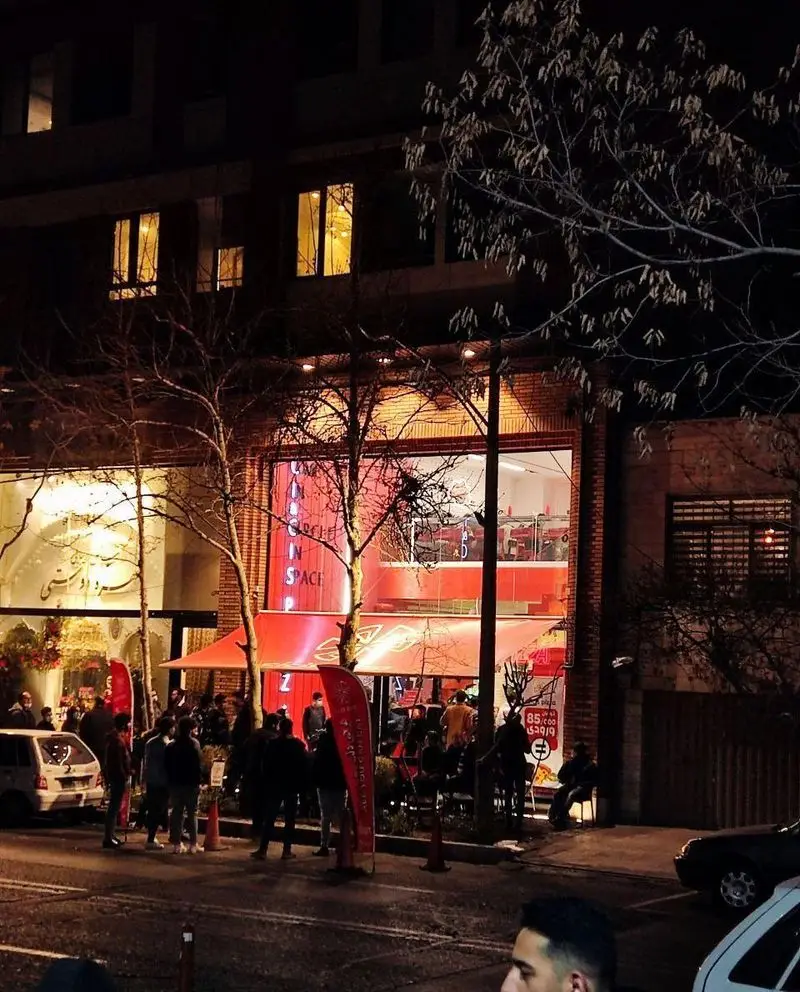 تصویری شبانه از پیتزا سیسیز، رستورانی شلوغ با مشتریان در فضای باز و داخلی، نشان‌دهنده محیط پرجنب‌وجوش پیتزافروشی.