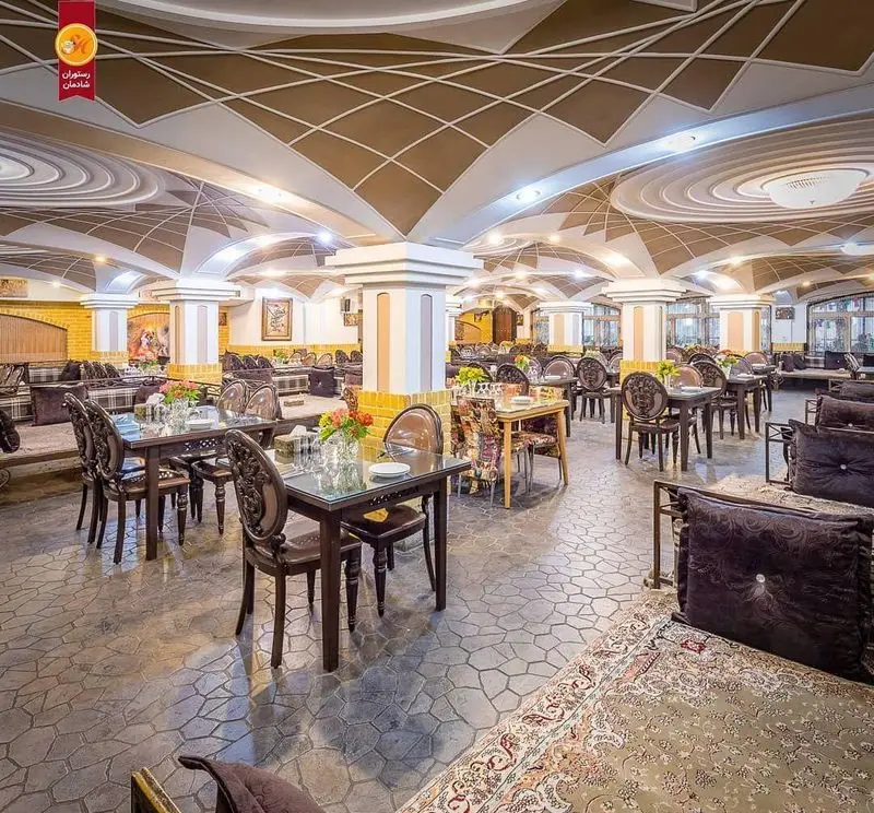 فضای داخلی رستوران شادمان با دکوراسیون مجلل و تلفیقی از سنت و مدرنیته. سقف‌های گنبدی طرح‌دار، ستون‌های باشکوه، میز و صندلی و تخت‌های سنتی.