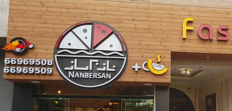 نمای بیرونی نانبرسان: تابلو با لوگوی پیتزا و کافه، شماره تماس 66969508 و 66969509 برای سفارش آنلاین و دلیوری غذا.