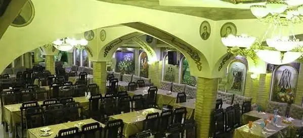 تصویری از فضای داخلی رستوران ایرانی هزار و یک شب، با دکوراسیون سنتی و چشم‌نواز، شامل میزها و صندلی‌های چوبی مرتب برای صرف غذا.