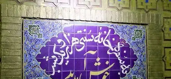 کاشی‌کاری سنتی با خوشنویسی فارسی "خانه سنتی هزار و یک شب" و طرح‌های آبی در ورودی رستوران ایرانی.