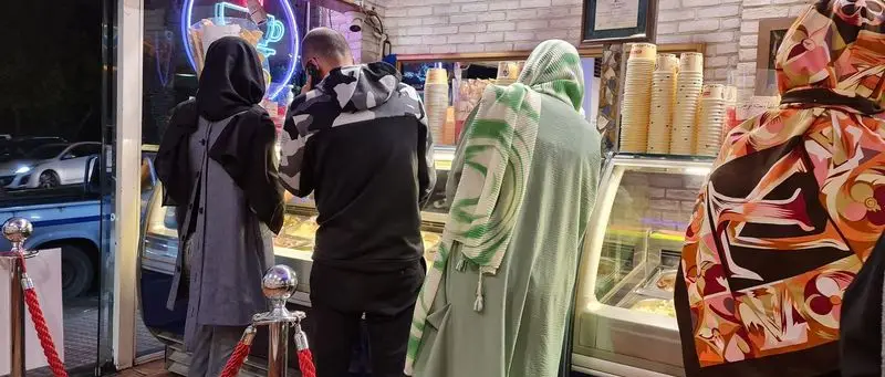 نمایی از مشتریان در حال مشاهده و انتخاب بستنی و دسرهای تازه در محیط گرم و دلنشین بستنی فروشی محبوب سان مار کو.