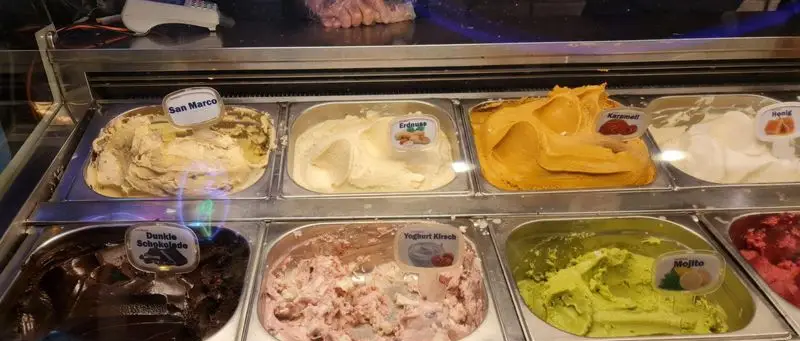 ویترین بستنی فروشی سان مارکو با تنوع طعم ها: شکلات تلخ، کارامل، بادام زمینی، عسل، ماست گیلاس و موهیتو، آماده سرو.