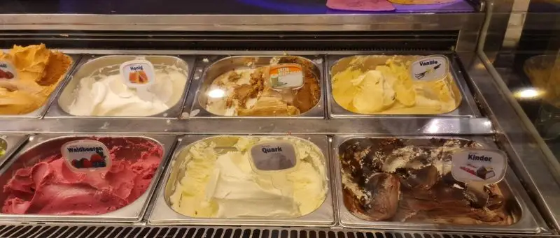 ویترین جذاب و متنوع بستنی سان مار کو با طعم‌های پرطرفدار وانیل، توت جنگلی، عسل، کوارک و کیندر شکلاتی.