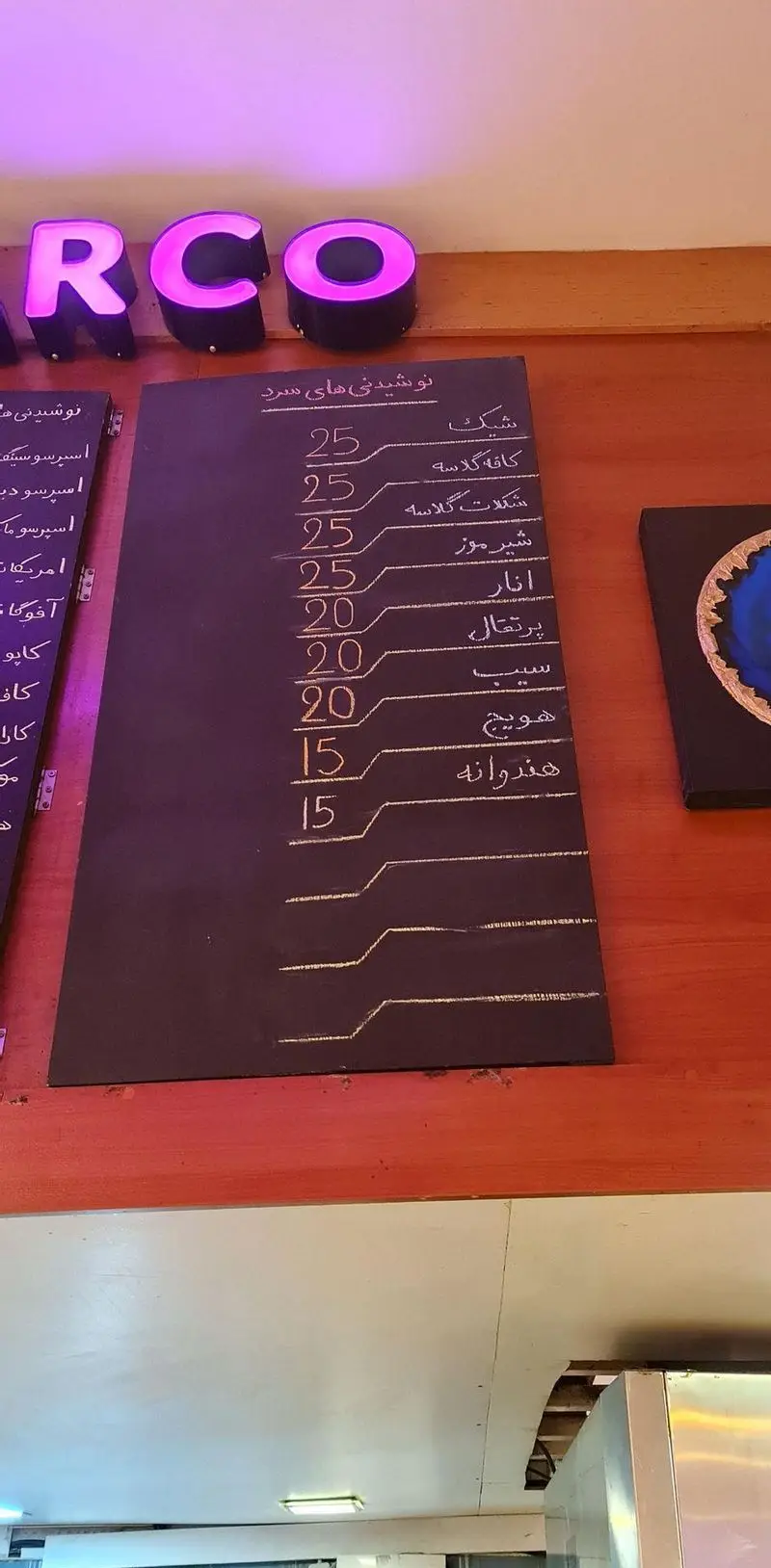 منوی کامل نوشیدنی های سرد بستنی سان مار کو در یک تخته سیاه با قیمت‌ها به زبان فارسی، شامل انواع شیک، آبمیوه‌های طبیعی و کافه گلاسه.