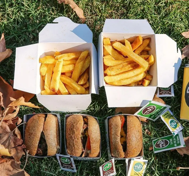 سیب زمینی سرخ کرده ترد و ساندویچ‌های متنوع فست فود د ل پ در جعبه‌های بیرون بر، ایده‌آل برای لذت بردن در فضای سبز.