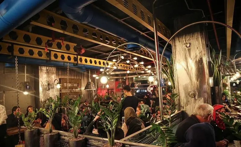 نمای داخلی شیک و مدرن فست فود د ل پ با دکوراسیون صنعتی، مشتریان در حال لذت بردن از غذا و نورپردازی زیبا در فضایی دلنشین.