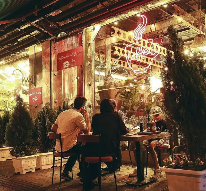 محیط دلنشین شبانه فست فود د ل پ؛ مشتریان در فضای باز رستوران ایتالیایی د ل پ در حال صرف غذا و نوشیدنی.