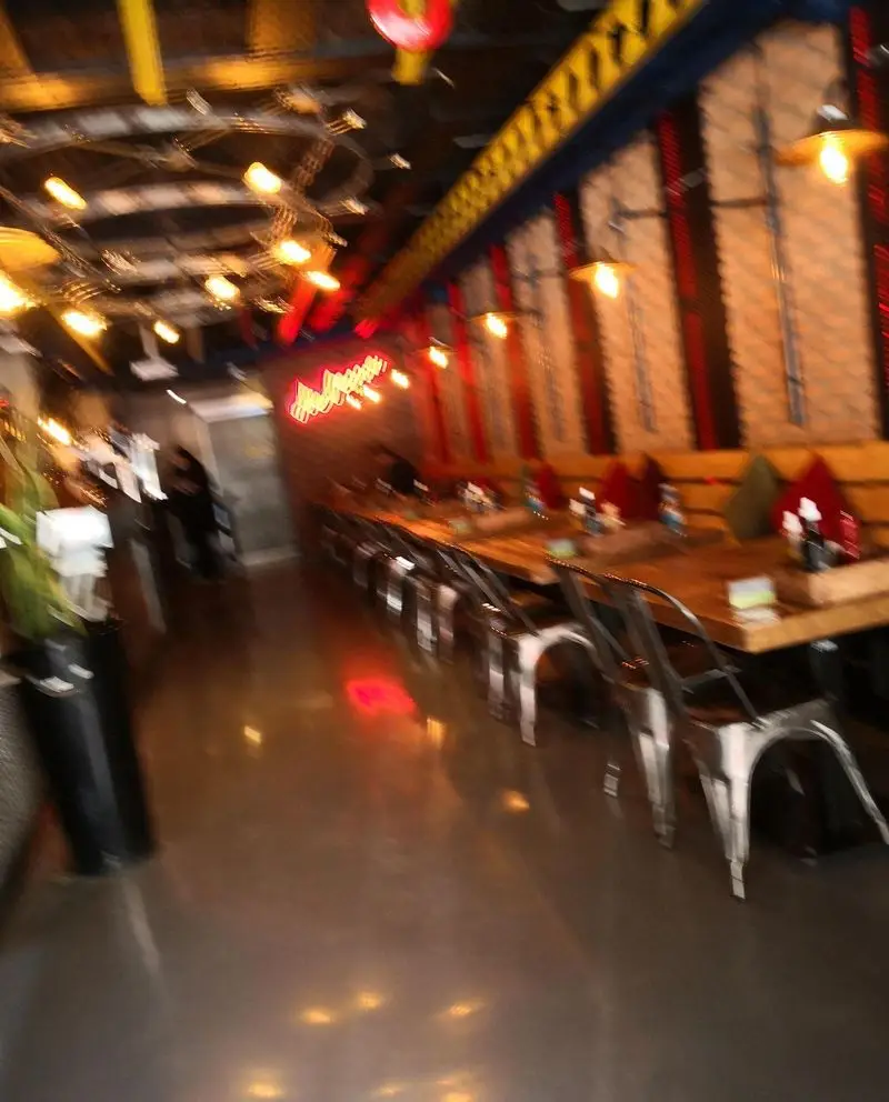 فضای داخلی مدرن و شیک فست فود د ل پ با میز و صندلی‌های چوبی و فلزی، نورپردازی گرم و محیطی دلنشین برای صرف غذاهای خوشمزه.