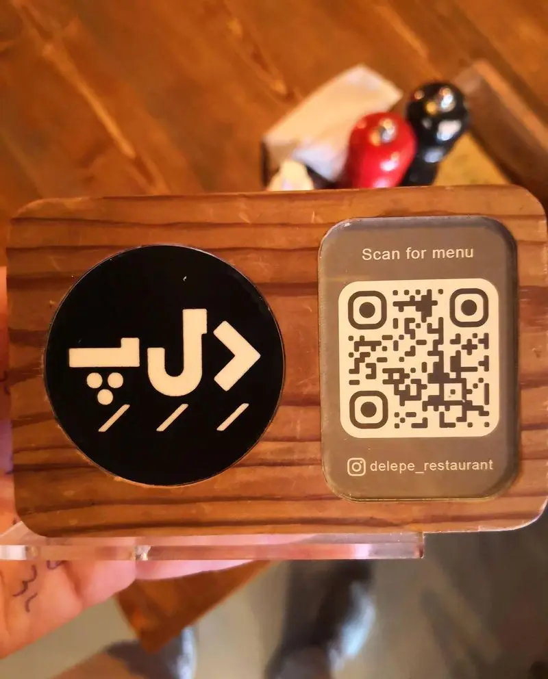استند چوبی شیک فست فود د ل پ شامل لوگو د ل پ و کد QR قابل اسکن برای منو دیجیتال، همراه با آیدی اینستاگرام delepe_restaurant.