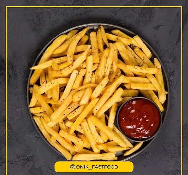 سیب زمینی سرخ کرده طلایی و خوش طعم فست فود اونیک در بشقاب مشکی با ادویه معطر و سس کچاپ.