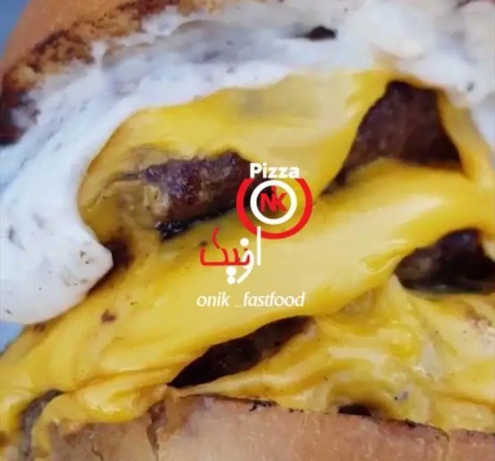 نمایی نزدیک از یک همبرگر خوشمزه و آبدار با پنیر ذوب شده و سفیده تخم مرغ در فست فود اونیک، انتخابی عالی برای دوستداران غذاهای لذیذ.