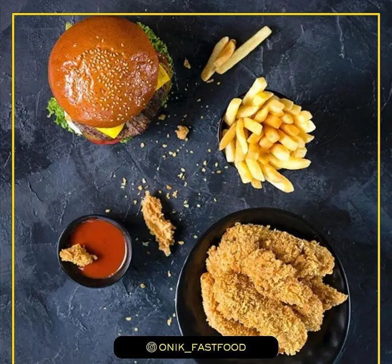 نمایی از بالای میز فست فود اونیک شامل یک برگر، سیب زمینی سرخ کرده طلایی، مرغ سوخاری ترد و سس کچاپ. غذای خوشمزه!