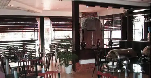 تصویری از فضای داخلی دلنشین فست فود اونیک، شامل میز و صندلی‌های مرتب، پنجره‌های نورگیر با پرده و بوفه آماده پذیرایی.